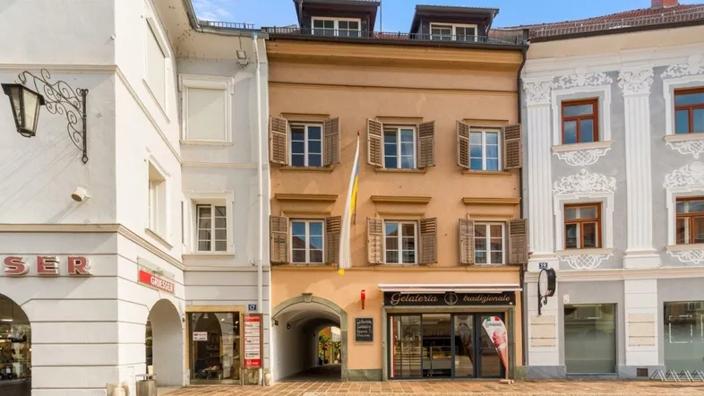 Historisches Gebäude mit Geschäften im Erdgeschoss und traditionellen Fensterläden in der Altstadt.