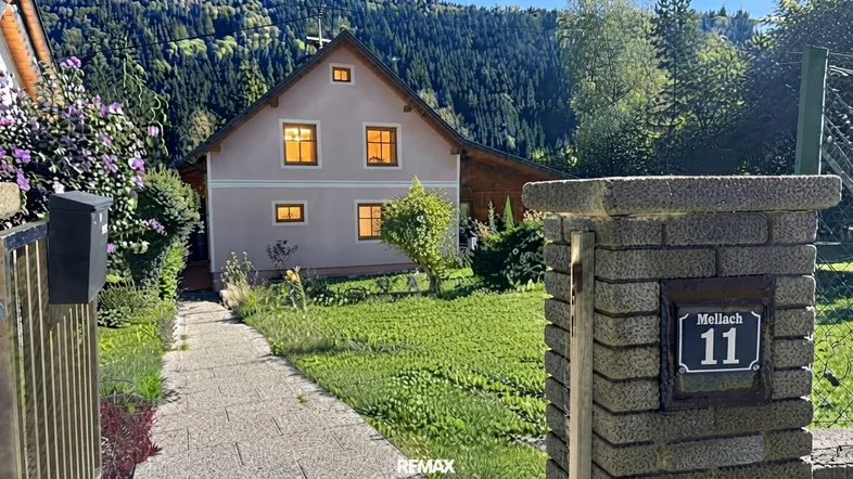 Charmantes Haus mit gepflegtem Vorgarten und Blick auf die umliegenden Berge.