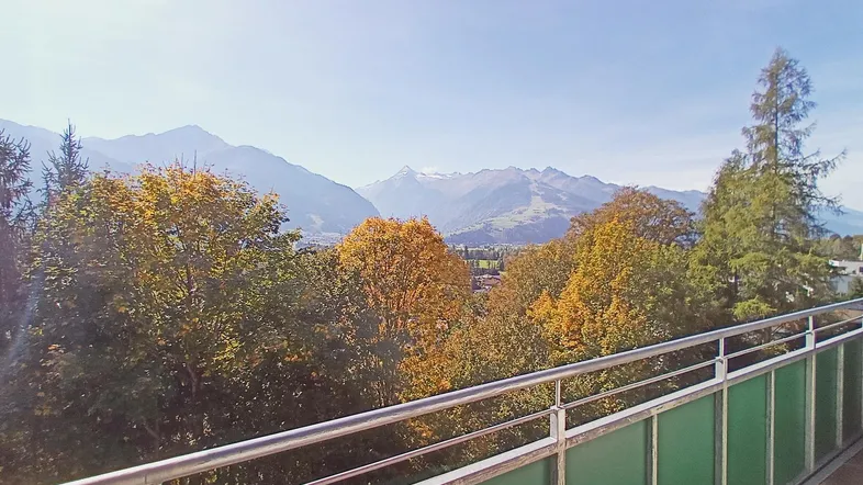 Panoramablick vom Balkon auf die umliegende Berglandschaft und herbstliche Bäume.