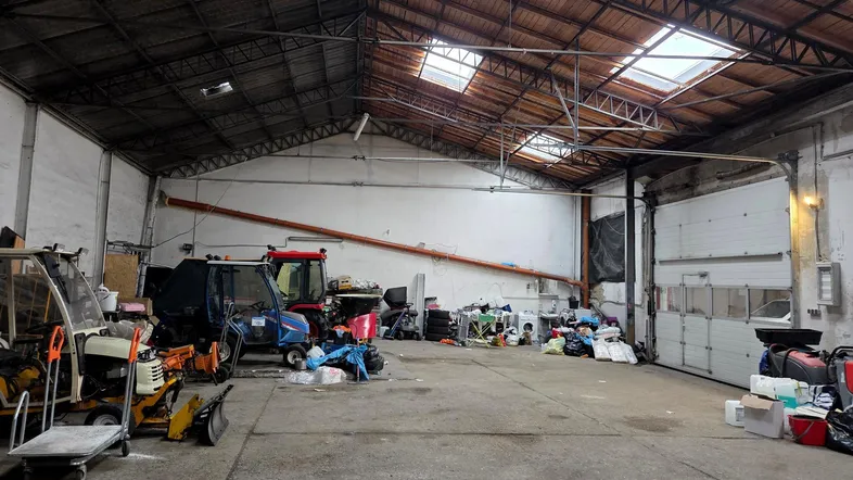 Große Lagerhalle mit hohen Decken, Oberlichtern und verschiedenen Geräten und Materialien auf dem Boden.