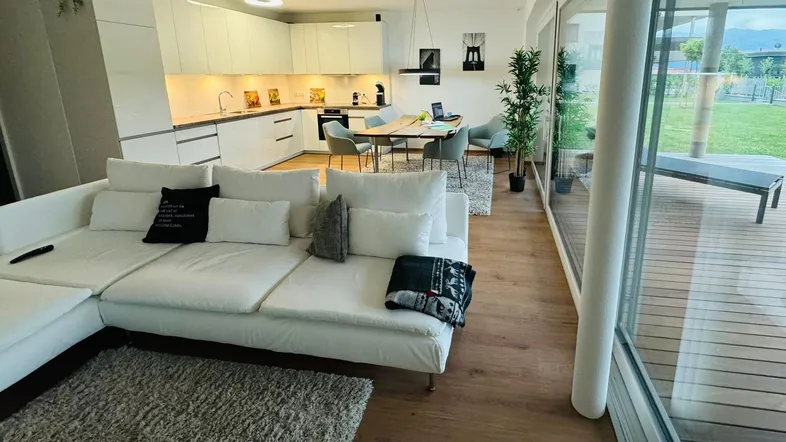 Helles, offenes Wohnzimmer mit integrierter Küche, Essbereich und Zugang zur Terrasse.