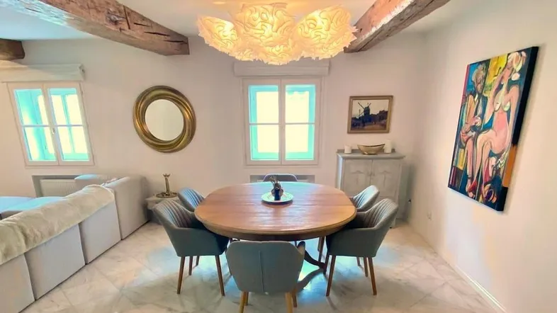 Helles Wohn- und Esszimmer mit Holzbalken, Marmorboden und modernem Esstisch.