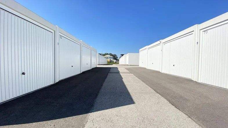 Reihen von Garagenboxen unter blauem Himmel, mit asphaltierten Zufahrten und viel Sonnenlicht.