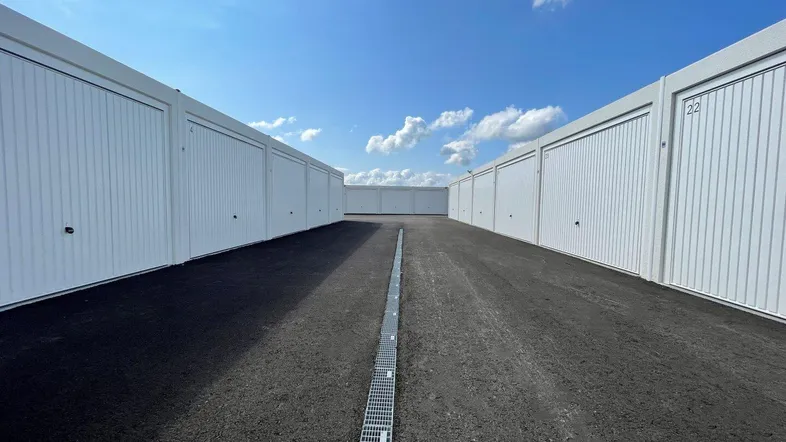 Reihen von modernen Garagenboxen unter blauem Himmel mit asphaltiertem Zufahrtsweg.
