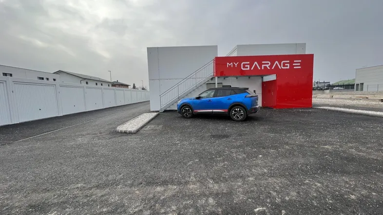 Außenansicht eines modernen Garagenkomplexes mit Parkplätzen und blauer Treppe.