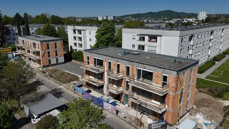 Luftaufnahme von Neubauten in Rohbauweise mit umliegenden Wohngebäuden und grüner Umgebung.