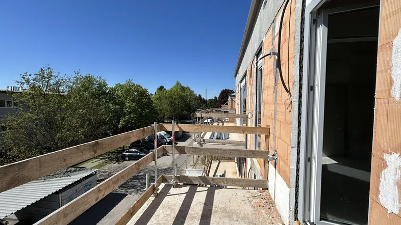 Balkon im Bau mit provisorischem Holzgeländer und Blick auf die Umgebung.