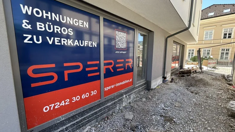 Erdgeschoss eines Neubaus mit Werbeaufschrift für Wohnungen und Büros zum Verkauf.