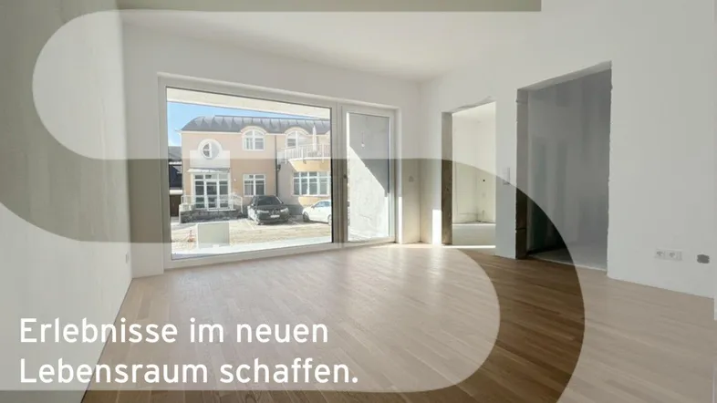 Heller, unmöblierter Wohnbereich mit Holzboden, großen Fenstern und Blick auf ein gegenüberliegendes Gebäude.