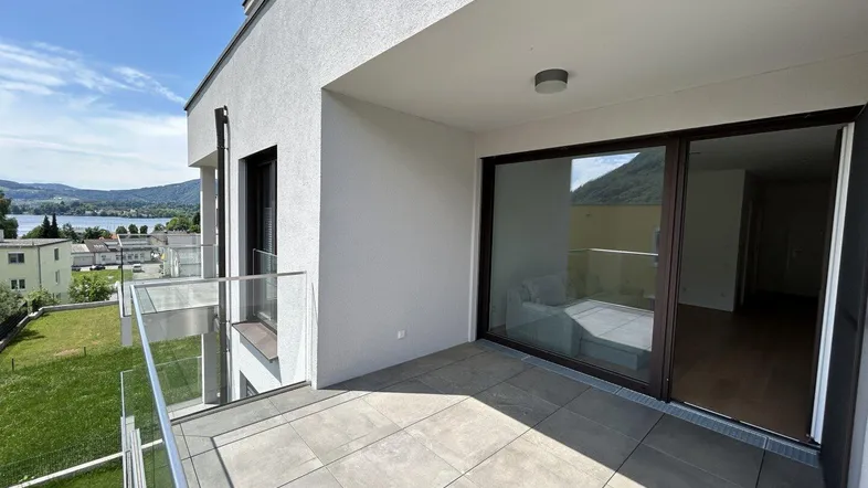 Heller Balkon mit Zugang zum Innenbereich und beeindruckendem Blick auf die umliegende Natur.