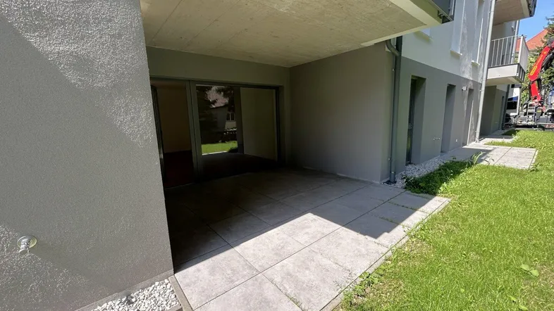 Erdgeschoss-Terrasse mit Fliesenboden und Zugang zum Gartenbereich eines modernen Gebäudes.