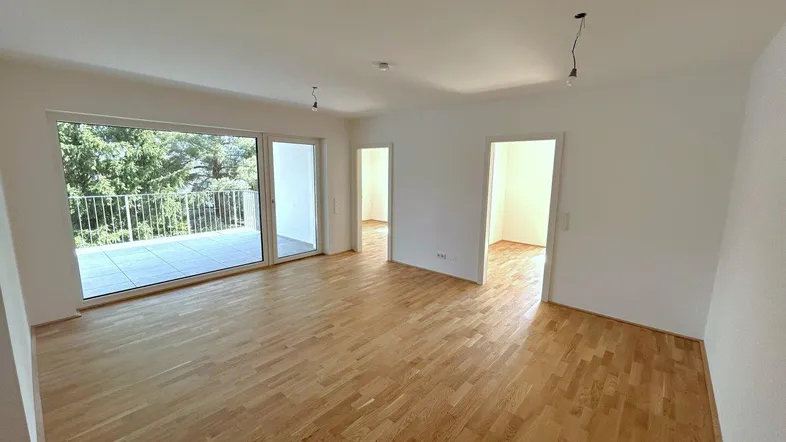Helles Wohnzimmer mit Parkettboden, weißen Wänden und Zugang zu einem großen Balkon mit Weitblick.
