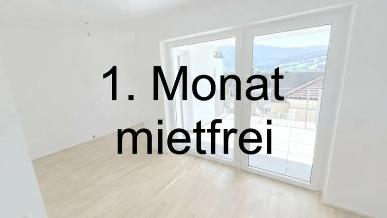 Heller, leerer Raum mit hellem Holzboden und großem Fenster mit Blick ins Grüne.
