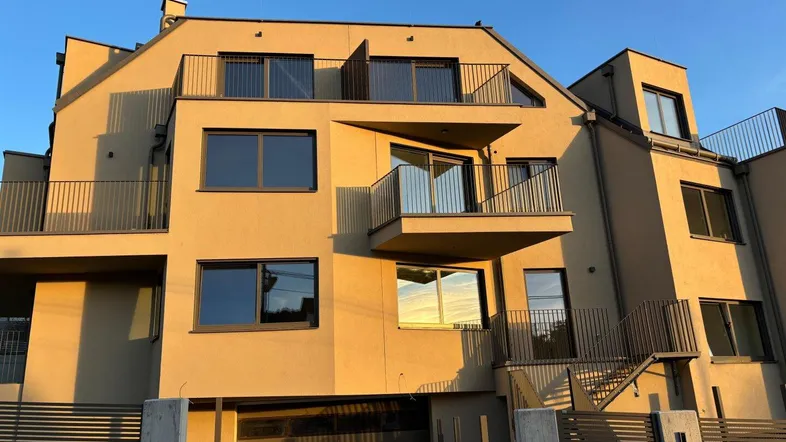 Moderne Wohnanlage mit mehreren Balkonen und integrierter Garage, beleuchtet von der Abendsonne.