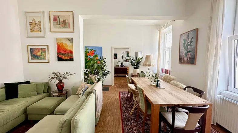 Geräumiger Wohn-Essbereich mit hellem Parkettboden, bequemen Sofas und einem großen Esstisch.