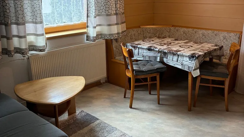 Gemütlicher Wohn- und Essbereich mit Holzwänden, Sofa und einer Eckbank am Esstisch.