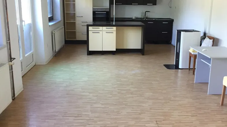 Geräumiger offener Wohnbereich mit Laminatboden und integrierter Küche mit Kochinsel.