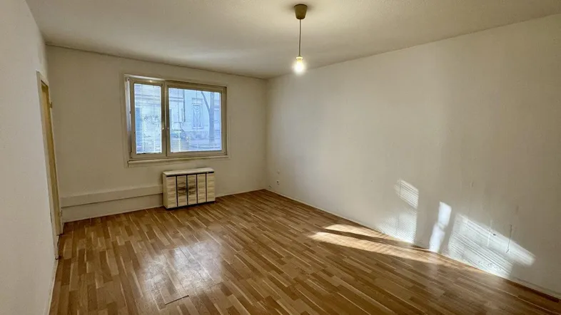 Helles Zimmer mit Parkettboden und weiß gestrichenen Wänden, ideal als Wohn- oder Schlafzimmer.