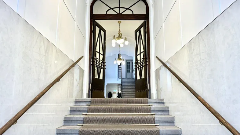 Großzügiger Eingangsbereich mit eleganter Treppe, Marmorverkleidung und prunkvollen Kronleuchtern.