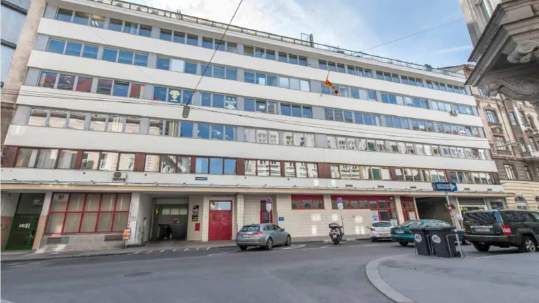 Ansicht der modernen Gebäudefassade mit zahlreichen Fenstern und Straßenzugang in urbaner Umgebung.