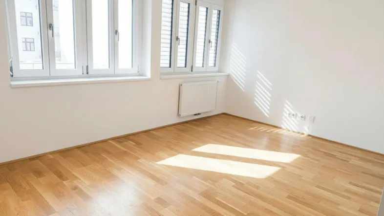 Helles Zimmer mit großen Fenstern, Parkettboden und viel natürlichem Licht.