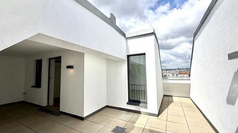 Geräumige Dachterrasse mit Fliesenboden und Blick auf die Stadt, ideal für Entspannung im Freien.