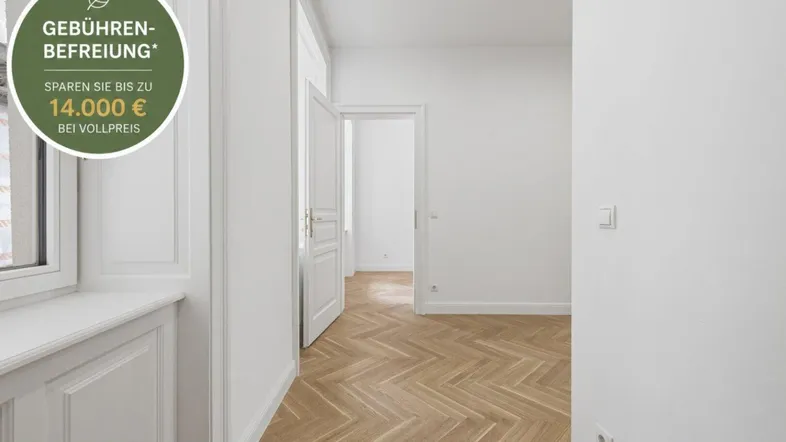 Heller Innenraum mit Fischgrätparkett, weißen Wänden und klassischen Türen, durch ein Fenster fällt natürliches Licht.