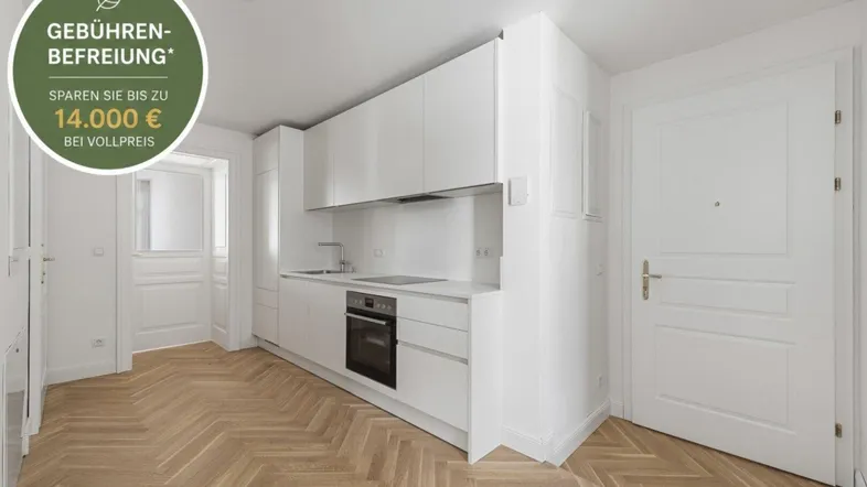 Moderne weiße Einbauküche mit integrierten Geräten und Fischgrätparkett in einem hellen Raum.