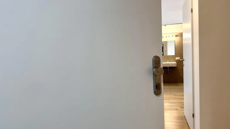 Eine offene Tür gibt den Blick auf einen hellen Flur und ein Badezimmer frei.