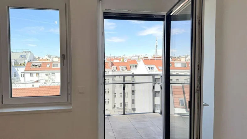 Heller Raum mit Zugang zu einem Balkon, der einen weiten Stadtblick bietet.