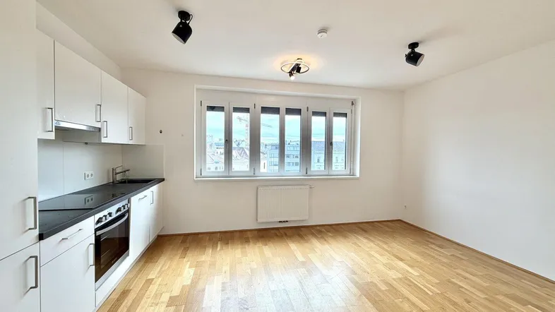 Helle Wohnküche mit modernen weißen Schränken, Holzboden und Blick aus dem Fenster.