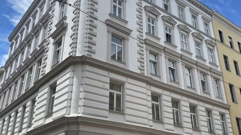 Historisches Eckgebäude mit klassischer Fassade und vielen Fenstern in städtischer Umgebung.