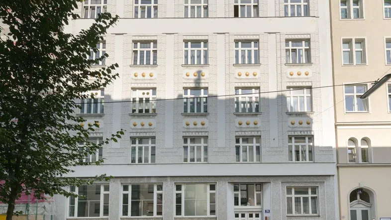 Ansicht der eleganten Fassade eines Mehrfamilienhauses mit vielen Fenstern und klassischem Design.