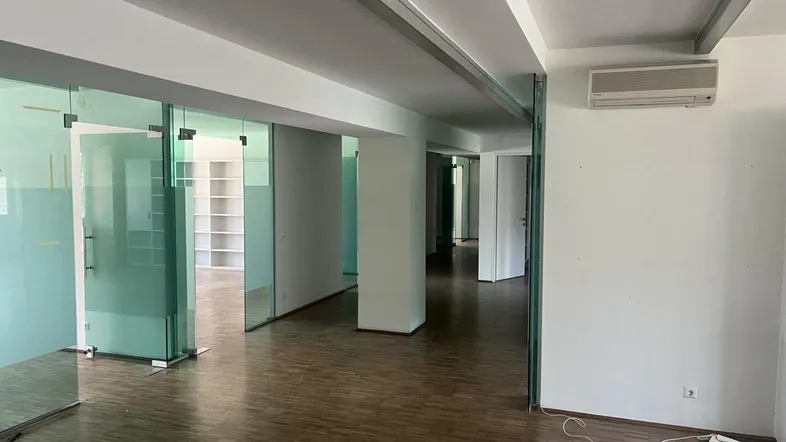 Geräumiger Bürobereich mit modernen Glaswänden, Holzfußboden und Klimaanlage, bietet flexible Arbeitsmöglichkeiten.