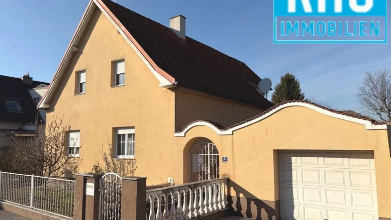 Gelbes Einfamilienhaus mit Satteldach, Garage und gepflegtem Vorgarten.