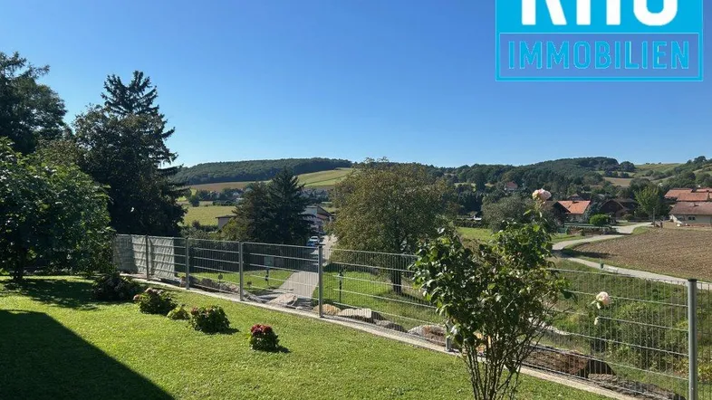 Grüner Gartenbereich mit Rasenfläche und weitem Blick über die hügelige Landschaft.