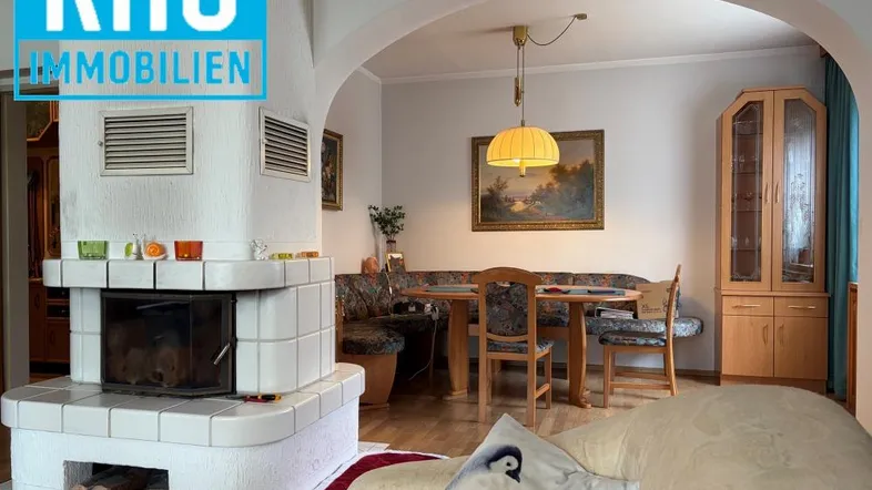 Gemütlicher Wohn-Essbereich mit Kaminofen, Holzboden und Durchgang zu weiteren Räumen.