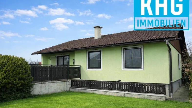 Seitenansicht des Hauses mit grünem Anstrich, braunem Dach und einem kleinen Rasenbereich.