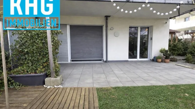 Große gepflasterte Terrasse mit kleinem Rasenbereich und Zugang zum Gebäude.