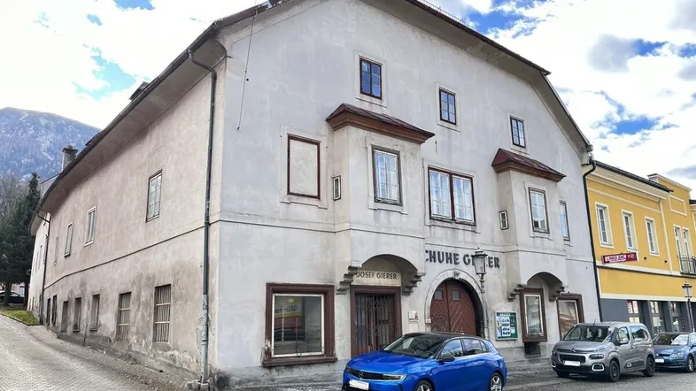 Altes Gebäude mit traditioneller Fassade und Geschäften im Erdgeschoss an einer Straße.