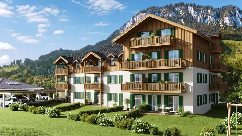 Eine moderne Wohnanlage im alpinen Stil mit Holzbalkonen und grünen Fensterläden vor einer Bergkulisse.