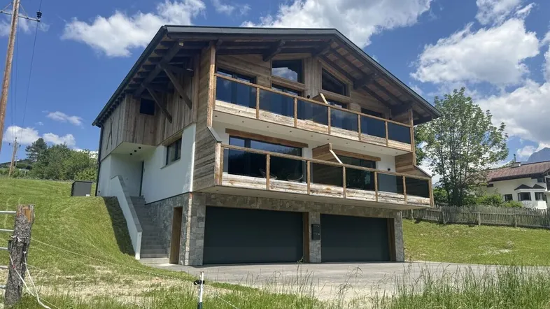 Modernes Chalet mit Holzfassade, großen Balkonen und integrierter Doppelgarage.