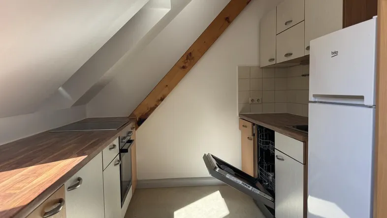 Helle Küche im Dachgeschoss mit Holzarbeitsplatten, Einbaugeräten und Dachschräge.