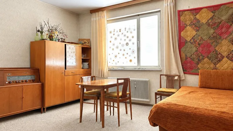 Gemütlicher Wohn- und Essbereich mit funktionalen Holzmöbeln und einem Fenster mit Tageslicht.