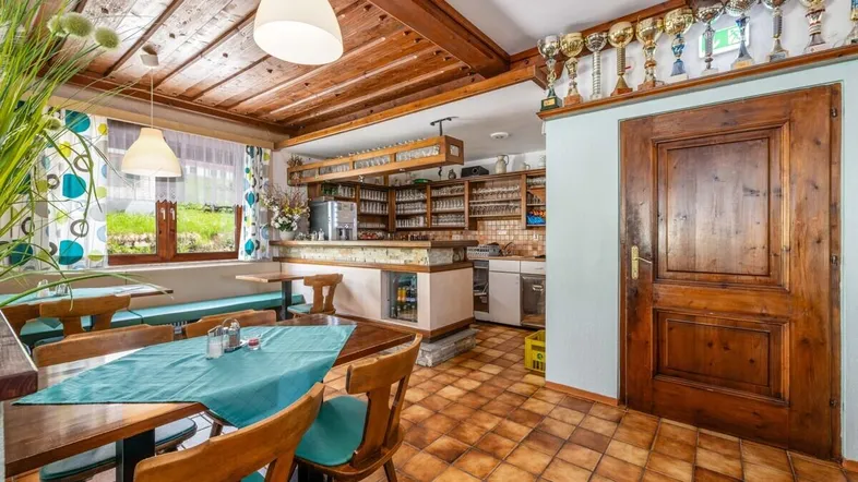 Rustikaler Essbereich mit Holzbalkendecke, Fliesenboden und einer Bar im Hintergrund, ideal für Gäste.