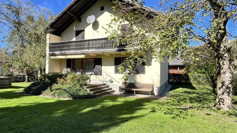Charmantes Haus mit Balkon, Garten und traditioneller Architektur unter blauem Himmel.