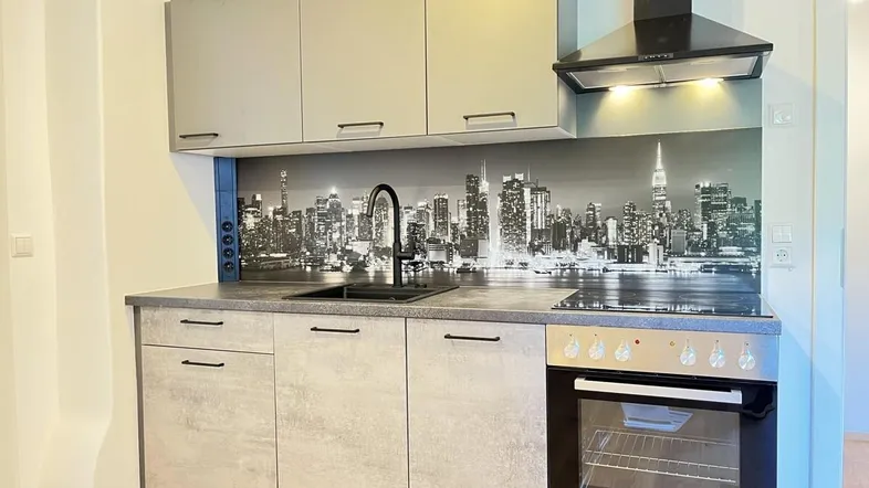 Moderne Küchenzeile mit grauen Fronten, integrierten Geräten und einer Stadtsilhouette als Spritzschutz.
