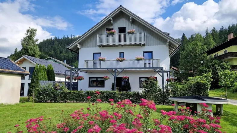 Charmantes Haus mit Balkonen, überdachter Terrasse und gepflegtem Garten in ländlicher Umgebung.