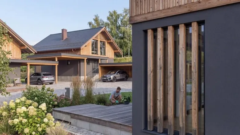 Nahaufnahme eines modernen Hauses mit Holzverkleidung, großen Fenstern und gepflegtem Vorgarten.