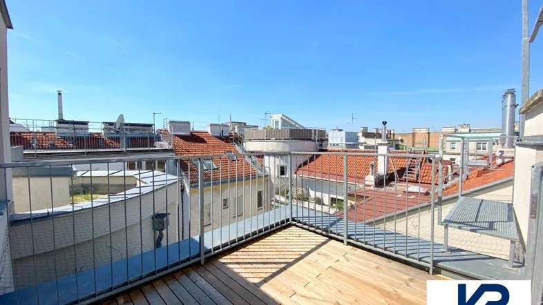 Geräumige Dachterrasse mit Holzboden und Metallgeländer, bietet einen weiten Blick über die Dächer der Stadt.